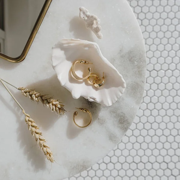在大理石桌子上镶嵌金耳环 配以镜子和麦茎的小巧时尚构图 马赛克瓷砖背景上的平铺 顶视图Bijouterie 珠宝概念 — 图库照片