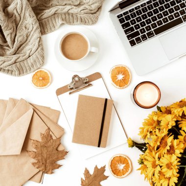 Ofis masası çalışma alanı dizüstü bilgisayarla süslenmiş sarı papatya çiçekleri, kahve fincanı, portakal dilimleri, ekose. Düz konum, üst görünüm serbest iş konsepti sosyal medya, dergi.