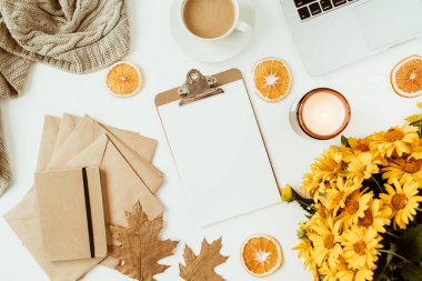 Sarı papatya çiçekleri buketi, kahve fincanı, portakal dilimleri ve ekoseyle süslenmiş ofis masası çalışma alanı. Düz konum, üst görünüm serbest iş konsepti sosyal medya, dergi.