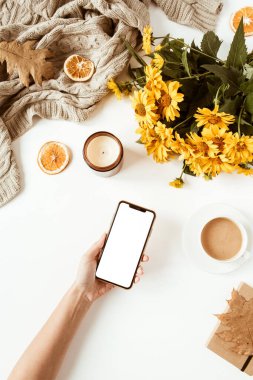 Kadınlar akıllı telefonu tutarlar. Ofis masası çalışma alanı. Düzlük, üst düzey kız patron iş konsepti. Battaniye, çiçek buketi, yapraklar, kahve fincanı. Sosyal medya şablonu.