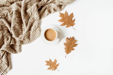Sütlü kahve, bej örgü ekose, beyaz arka planda kuru yapraklar. Düz yatış, üst görünüm.
