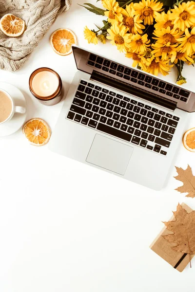 Laptop, battaniye, çiçek buketi ve beyaz arka planda yaprakları olan düz bir ofis masası çalışma alanı. Üst düzey kız patron serbest iş, iş hala hayat konsepti.