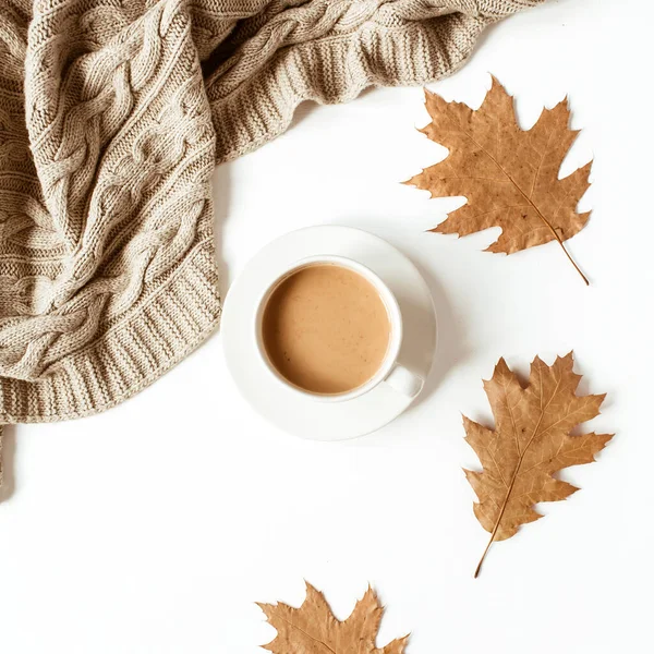 Sütlü kahve, bej örgü ekose, beyaz arka planda kuru yapraklar. Düz yerde, üst tarafta. En düşük sonbahar sabahı kahvaltı kompozisyonu.