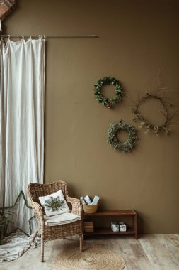 Zeytin duvarındaki köknar iğneleri ve dallardan yapılmış yuvarlak ev yapımı çelenk çerçeveleri. Noel kutlaması süsü. Yeni yıl kompozisyonu. Modern iç tasarım.