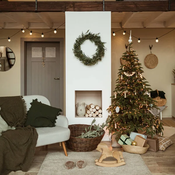 Modern iç tasarım konsepti. Noel ağacı, çelenk çerçevesi, şömine, kanepe, halı ile süslenmiş rahat bir oturma odası. Noel / Yeni Yıl kutlamaları.