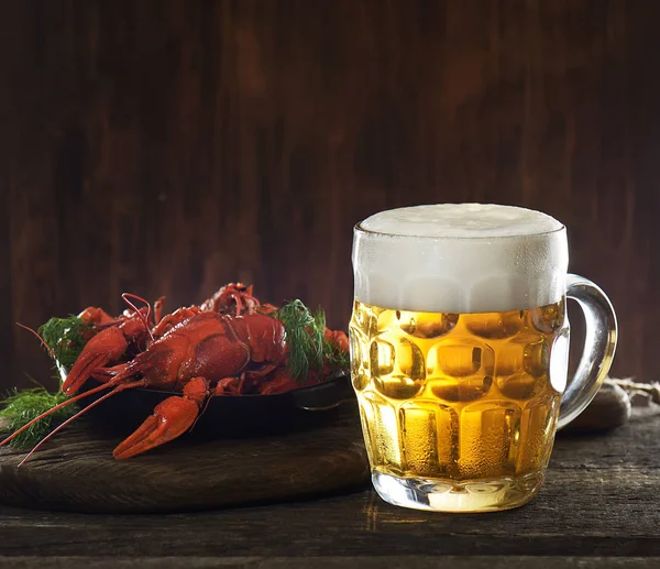 glass of beer and boiled crayfish wooden background