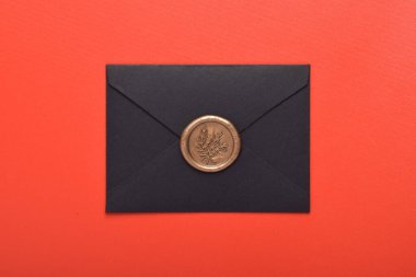 Kırmızı arkaplanda balmumu mühürlü siyah zarf