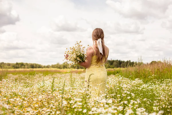 A girl in a white dress walks in a chamomile field with daisies — Stock Photo, Image