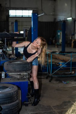 Araba servisindeki bir kız lastiklerle çalışır.