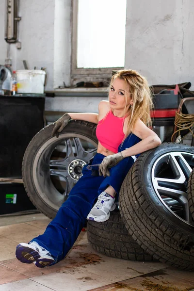 자동차 봉사를 하는 한 소녀는 타이어를 다루는 일을 한다 — 스톡 사진