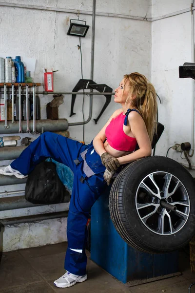 Een meisje in een auto service werkt met banden — Stockfoto