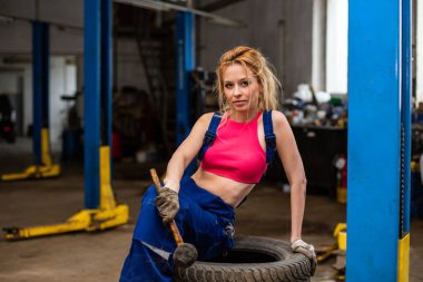 Araba servisindeki bir kız lastiklerle çalışır.