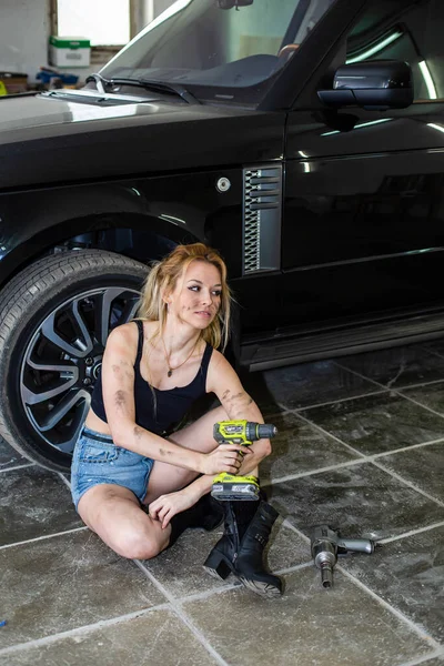 Een meisje in een auto service werkt met banden — Stockfoto
