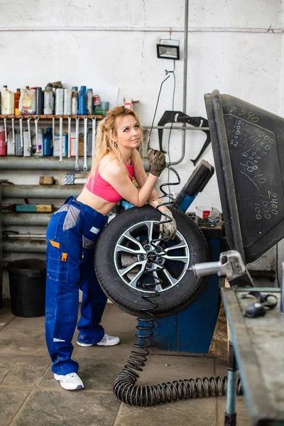 Девушка в автосервисе работает с шинами — стоковое фото