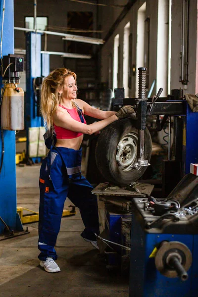 Девушка в автосервисе работает с шинами — стоковое фото