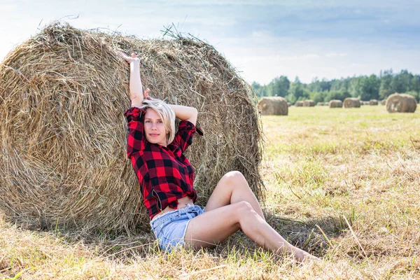坐在干草捆上的年轻女子 — 图库照片