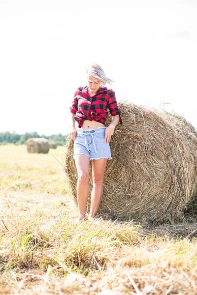 Ung kvinna sitter på höbalen — Stockfoto