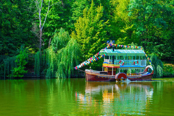 Photo of a beautiful tourist ship on a lake in a park at summer