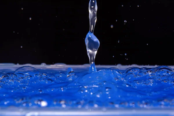 Foto van blauw water druppelen en druppels op zwarte achtergrond — Stockfoto