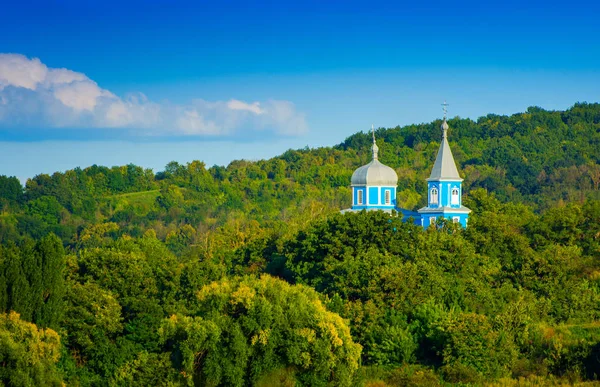 Photo of blue church between green trees — Stock Photo, Image