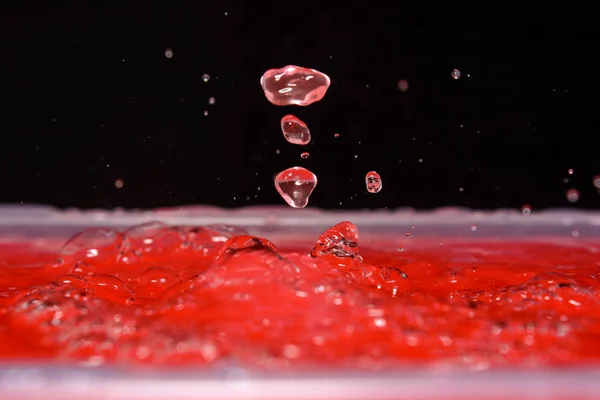Foto van water druppels vallen op water en splash op zwarte achtergrond — Stockfoto