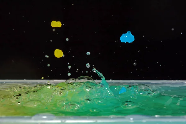 Foto van water druppels vallen op water en splash op zwarte achtergrond — Stockfoto