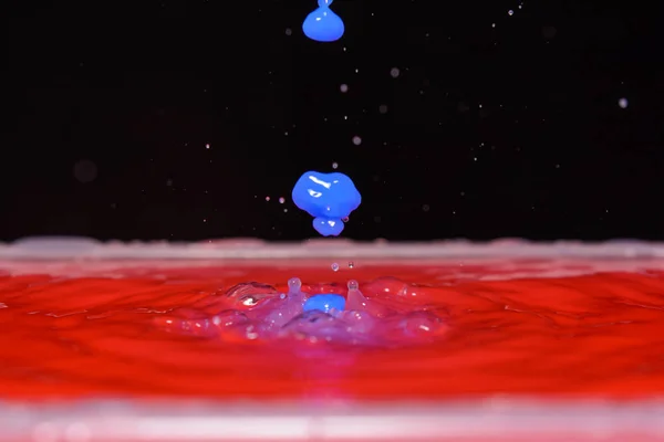 Foto van rode water druppelen en druppels op zwarte achtergrond — Stockfoto