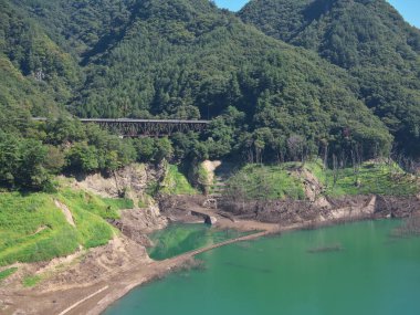 Gunma, Japonya - 7 Eylül 2025: Japonya 'nın Gunma kentindeki Yamba Barajı' nın suları altında kuraklık, kullanılmayan demiryolu rayları, yollar, bodrumlar ve ağaçlar nedeniyle ortaya çıktı.