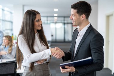 Genç yakışıklı iş adamı genç bayan meslektaşını şirketteki terfisi için tebrik ediyor..