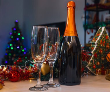 Şampanya bardakları, mumlar ve dekore edilmiş bir ağacın olduğu şenlikli bir yeni yıl sahnesi.