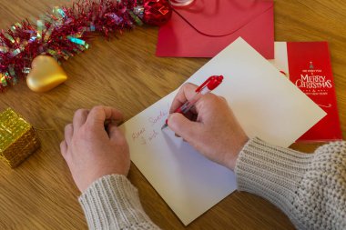 Noel Baba 'ya süslü festival masasında Noel mektubu yazan bir kadın.