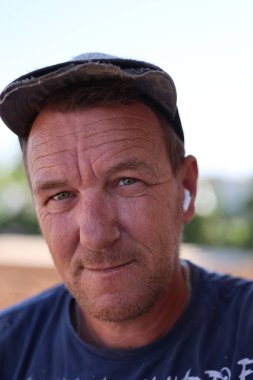 Düşünceli bir ifadesi ve gülümsemesi olan orta yaşlı bir adamın samimi bir portresi.