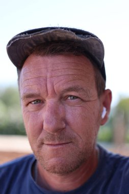 Düşünceli bir ifadesi ve gülümsemesi olan orta yaşlı bir adamın samimi bir portresi.