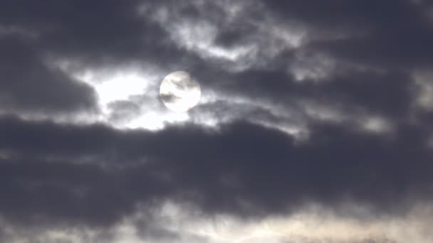Le disque solaire est vu à travers des nuages sombres en mouvement rapide .