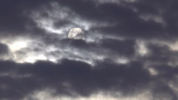 Le disque solaire est vu à travers des nuages sombres en mouvement rapide .