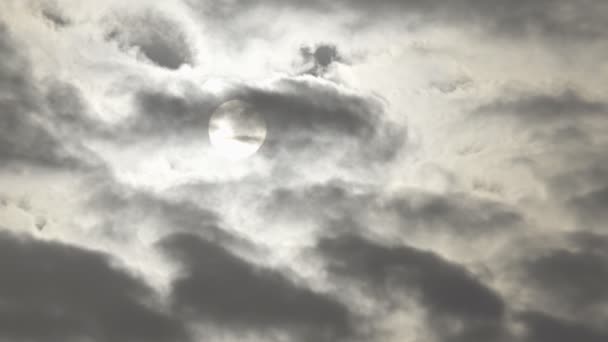 Le disque solaire est vu à travers des nuages sombres en mouvement rapide .