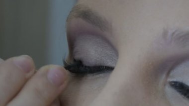 Kız mavi gözler için profesyonel makyaj yapar. Özel bir fırça kullanarak gözü siyahla çevreler. Bu gözleri daha anlamlı hale getirir