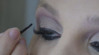 Kız mavi gözler için profesyonel makyaj yapar. Özel bir fırça kullanarak gözü siyahla çevreler. Bu gözleri daha anlamlı hale getirir