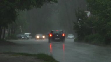 Şiddetli bahar yağmuru yolda araba ve yoldan geçen insanlar ile sokakları sel.