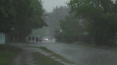 Şiddetli bahar yağmuru yolda araba ve yoldan geçen insanlar ile sokakları sel.