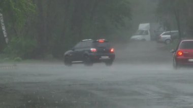 Şiddetli bahar yağmuru yolda araba ve yoldan geçen insanlar ile sokakları sel.