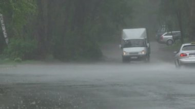 Şiddetli bahar yağmuru yolda araba ve yoldan geçen insanlar ile sokakları sel.