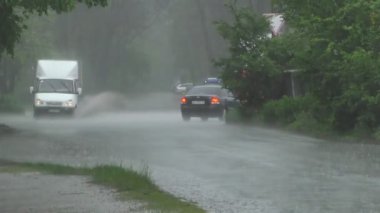 Şiddetli bahar yağmuru yolda araba ve yoldan geçen insanlar ile sokakları sel.