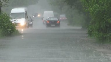 Şiddetli bahar yağmuru yolda araba ve yoldan geçen insanlar ile sokakları sel.