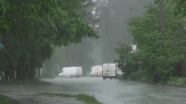 Şiddetli bahar yağmuru yolda araba ve yoldan geçen insanlar ile sokakları sel.