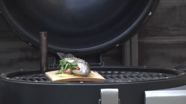 Kömür üzerinde pişirilen alabalık balık hizmet için otlar ve baharatlar serpilir.