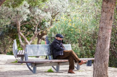 Barcelona - Mart, 2018: yalnız Barcelona'da bir parkta bir bankta oturan üst düzey adam