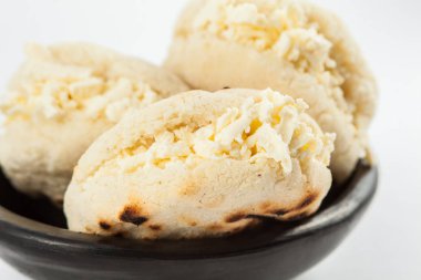 Kolombiyalı geleneksel beyaz Mısır arepa beyaz arka plan üzerinde siyah bir seramik tabak içinde rendelenmiş peynir ile doldurulmuş