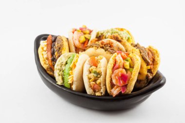 Beyaz arka plan üzerinde siyah bir seramik tabak arepas çeşitli dolguları ile servis
