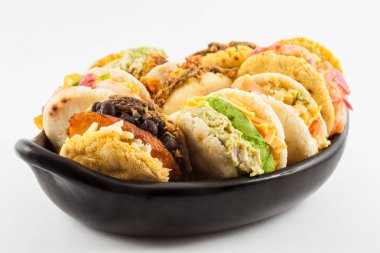 Arepas with assorted fillings served in a black ceramic dish on white background clipart